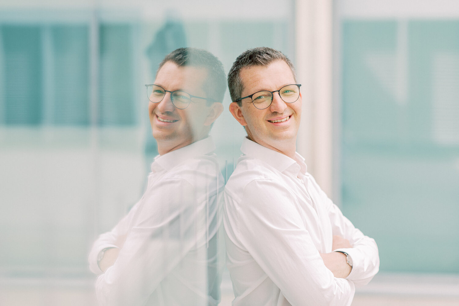 Robert Liebhold lehnt an einer Glasfassade, in der sich sein Profil spiegelt