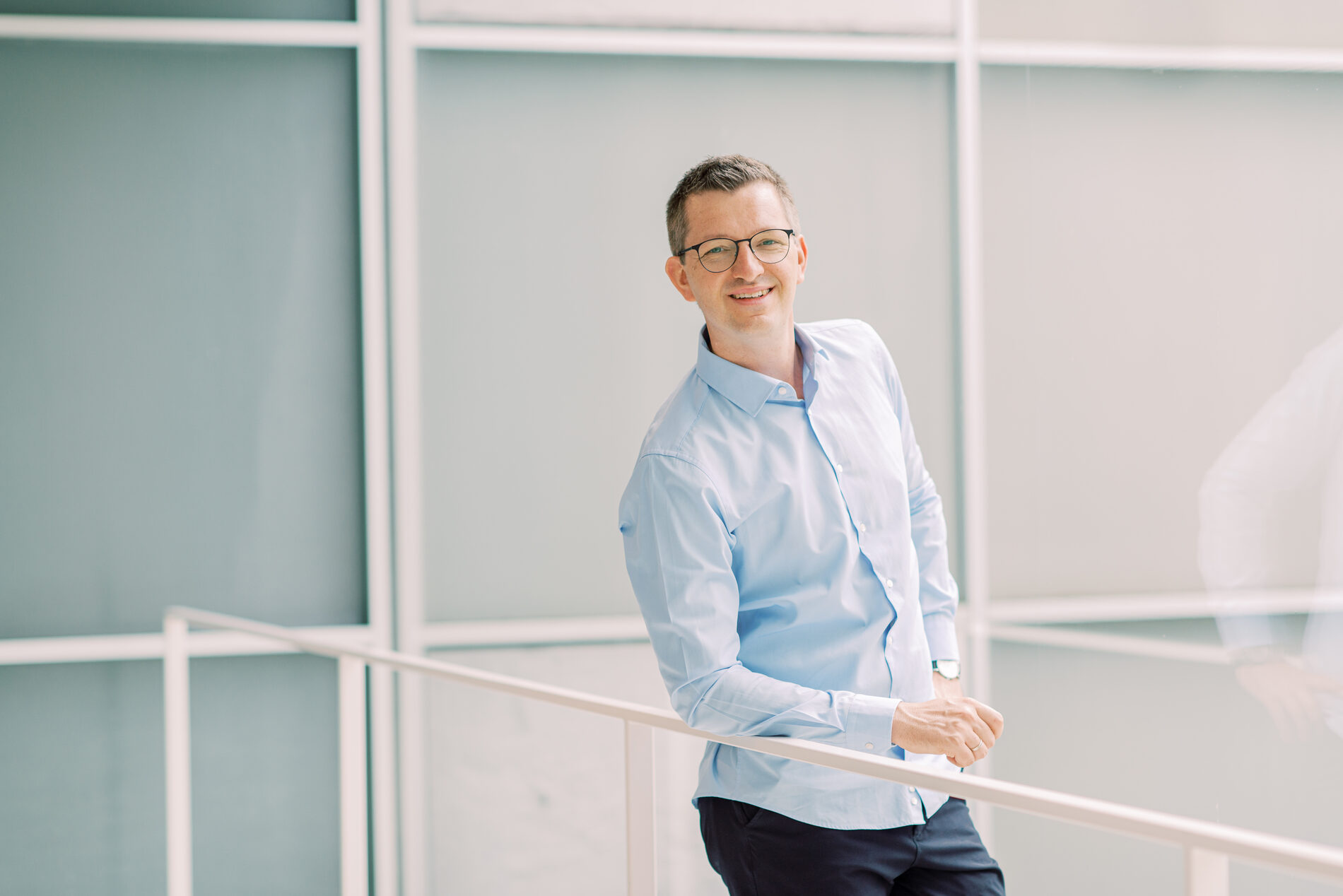 Robert Liebhold, Vertriebsexperte, an einem Treppengeländer in einem hellen Bürogebäude